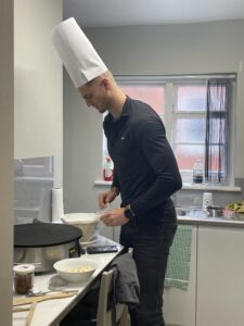Coel cooking pancakes with a chefs hat